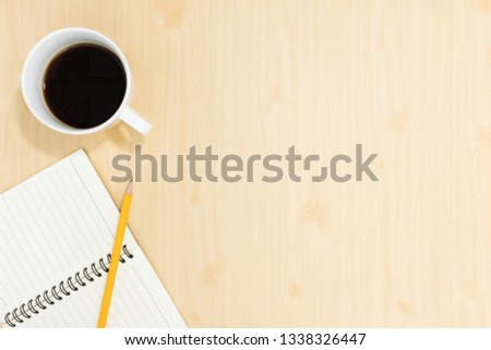 Top view of notebook pencil and cup of coffee on wood table background.Business desk minimal style concept with copy space for any design.Flat lay.