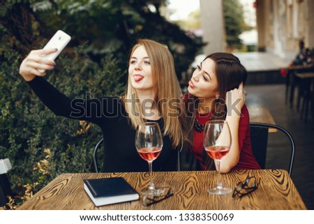 Young and pretty girls sitting in a cafe at the table with wine 