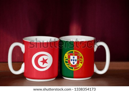 Portugal and Tunisia flag on two cups with blurry background