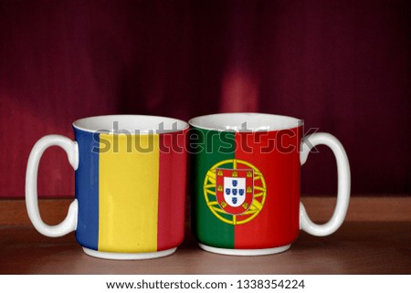 Portugal and Romania flag on two cups with blurry background