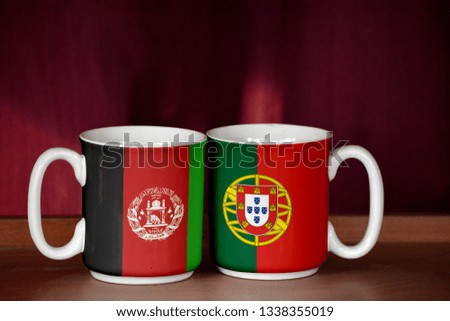 Portugal and Afghanistan flag on two cups with blurry background