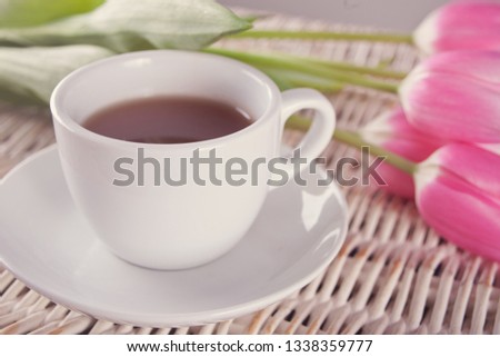 A cup of tea and pink tulips on the table