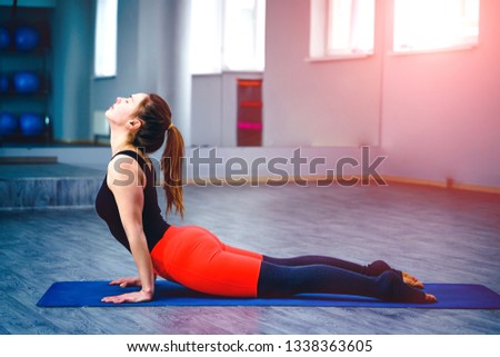 Young woman practicing yoga position in an indoor gym studio. Concept of healthy lifestyle.