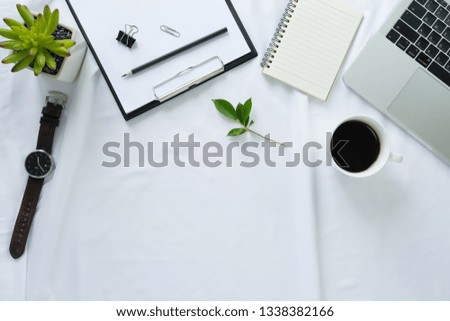 Flay lay, Top view office table desk with laptop, notebook, keyboard, coffee cup, watch, pencil, leaves with copy space fabric white  background.