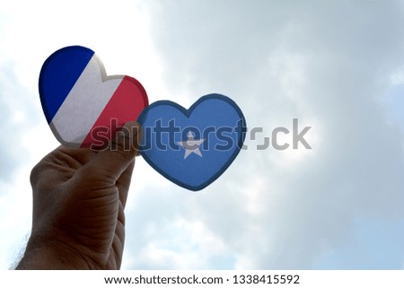 Hand holds a heart Shape France and Somalia flag, love between two countries