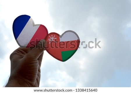 Hand holds a heart Shape France and Oman flag, love between two countries