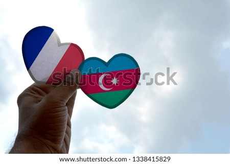 Hand holds a heart Shape France and Azerbaijan flag, love between two countries