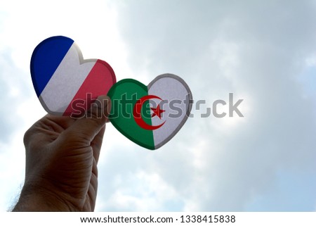 Hand holds a heart Shape France and Algeria flag, love between two countries