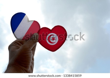 Hand holds a heart Shape France and Tunisia flag, love between two countries