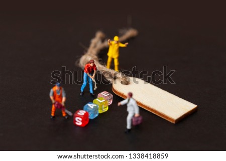 Discount sale concept. Miniature people work with the label for clothes. Close up. 