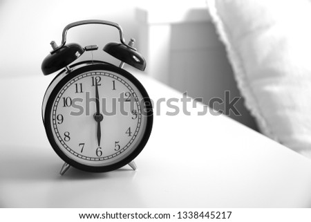 Wake up concept. Close up view of alarm-clock in morning bedroom environment. An image of a retro clock showing 06:00 am.                                      