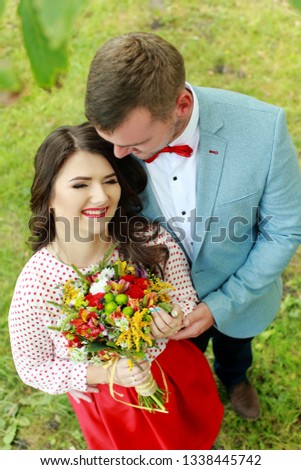 young beautiful couple bride and groom are standing in the park at sunset and smiling bride with red hair and beautiful dress the groom is dressed stylishly