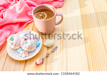 Romantic sweet breakfast concept. Green tea, lemon, meringue (cake). On wooden background with pink cloth