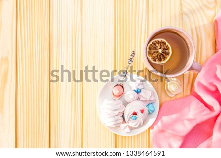 Romantic sweet breakfast concept. Green tea, lemon, meringue (cake). On wooden background with pink cloth, top view