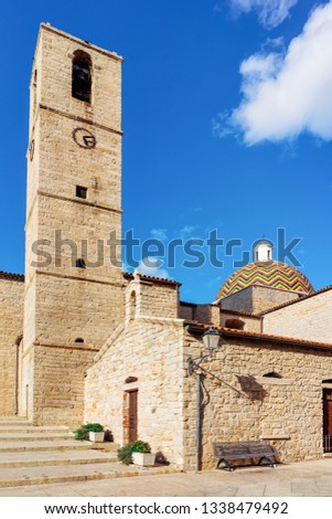 Cupola of Chiesa di San Paolo Apostolo Church and Bell Tower in Old city of Olbia on Sardinia Island in Italy. Cathedral and Belfry in Sardegna island. Blue sky with white clouds on background.