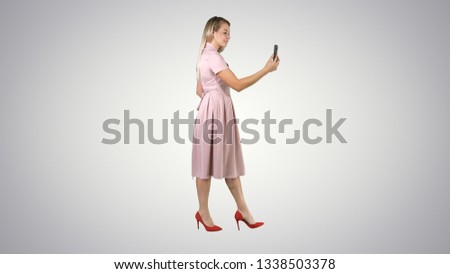 Cute sweet gorgeous nice stunning adorable good-looking good-dressed lady making selfie while walking on gradient background.