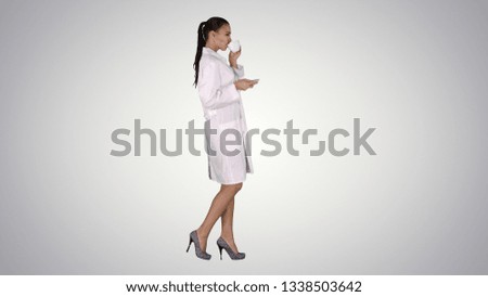 Young nurse relaxing drinking coffee or tea while walking on gradient background.