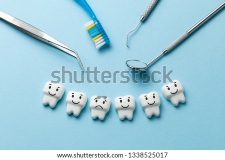 White tooth with caries on blue background  and dentist tools mirror, hook