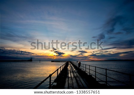 December dawn at the mouth of the River Blyth in Northumberland, North East England. This view shows the old Wooden Pier, damp from overnight rain, disappearing towards the horizon and the rising sun.