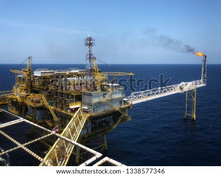 Offshore rig platform or Offshore oil and gas Accommodation Platform or Living Quarter and Production plant with a calm sea and blue clear sky with active flare boom and gangway with remote platform