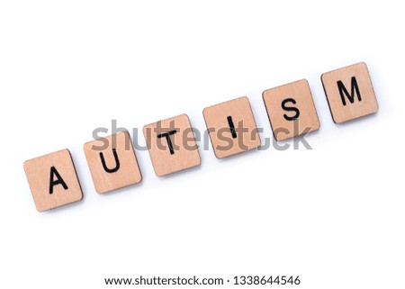 The word AUTISM, spelt with wooden letter tiles over a white background. 