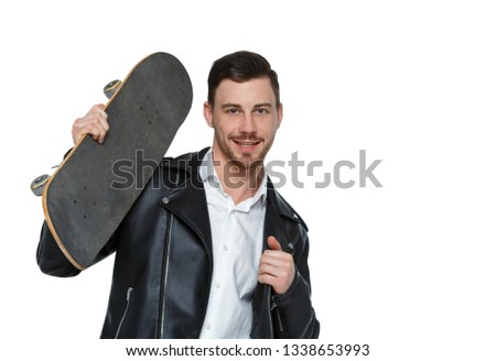 A man with a skateboard. A guy in stylish clothes and trousers posing with a board for skating. Front view. Isolated on white background. Stylish guy in a leather jacket posing with  skate 