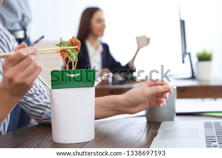 Office employee having noodles for lunch at workplace, closeup. Food delivery