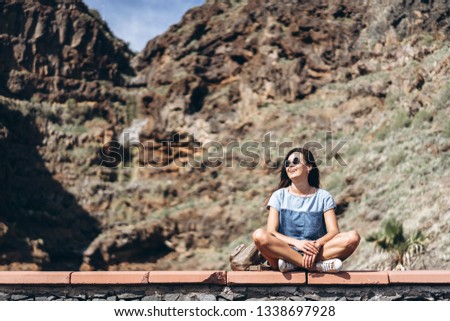 Happy pretty tourist brunette girl relaxing near rock