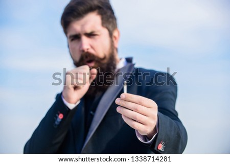 Guy cigarette enjoy nicotine influence. Man with beard mustache hold cigarette. Cigarettes help us with everything from boredom to anger management. Bearded hipster smoking cigarette sky background.