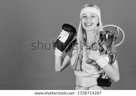 Sport shop assortment. Girl successful modern woman hold golden goblet of sport champion and equipment blue background. Sport for every day. How to find time for everything. Sport equipment store.