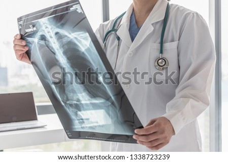 Doctor with radiological chest x-ray film for medical diagnosis on patient’s health on asthma, lung disease and bone cancer illness Royalty-Free Stock Photo #1338723239