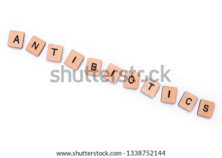 The word ANTIBIOTICS, spelt with wooden letter tiles over a white background. 