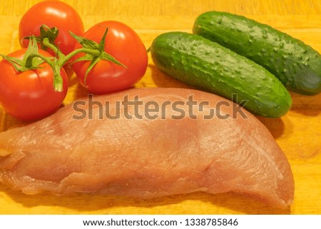 Raw duck breast with tomatoes and cucumbers. On the chopping Board.