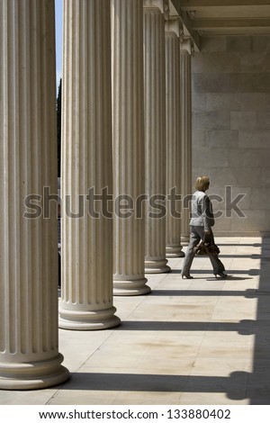 Elegant business woman behind the columns of entrance to Mestrovic gallery in Split; Croatia