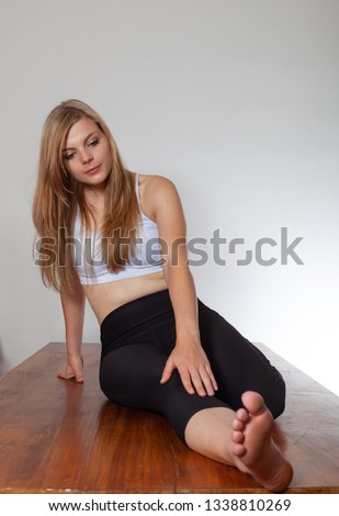Young woman stretching, practicing yoga, barefoot.