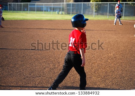 Youth baseball player on third base getting ready to run.