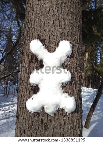 Strange snowman in the form of a silhouette of a hare on a tree background.