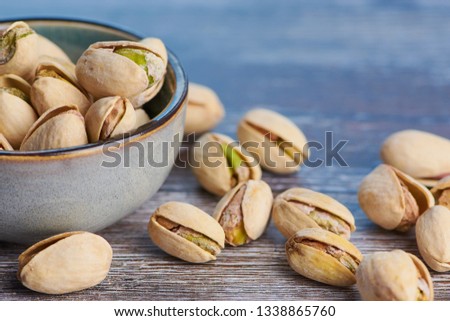 close up color picture of pistachios roasted and salted in a ceramic bowl on a wooden surface