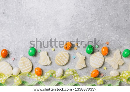 sugar easter cookies with colorful chocolate shape of eggs candy on grey background. Top view
