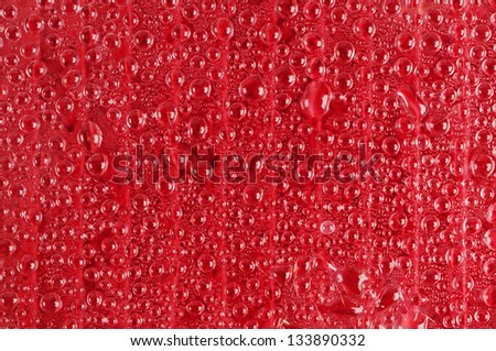 Water drops on red transparent glass close up