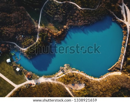 Aerial top down view of pond or lake for fishing in spring mountain forest with pathways, drone shot, toned