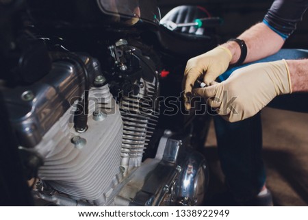 Man fixing bike. Confident young man repairing motorcycle near his garage.