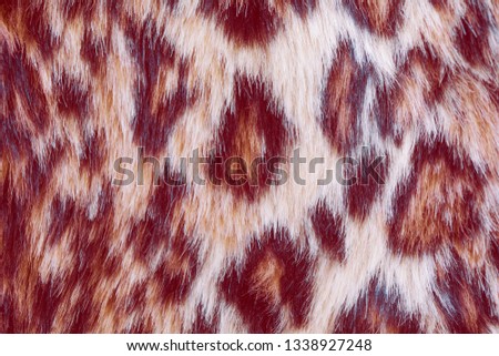 Actual colors for this season - a shade of orange and coral color. Leopard background, synthetic fur. Imitation leopard print texture. 
