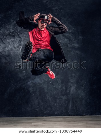 Emotional hip-hop style dancer performing dance elements. Studio photo against a dark textured wall