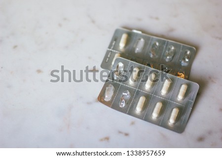 White pills in silver packaging. Half consumed with some pills remaining. Sitting on top of marble table top. 
