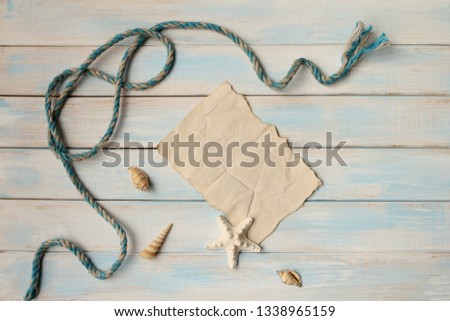 Seashells and star on blue wooden background and sheet of old paper as a vacation concept with copy space