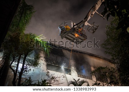 Firefighters action water spray on firefighter crane in a warehouse fire accident
