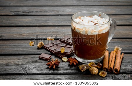Hot chocolate with cinnamon and marshmallows. On a wooden background.