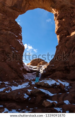 Photographer taking pictures of Turret arch early winter with snow and ice on the red rock