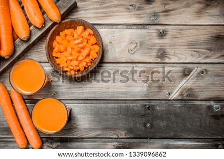 Carrot juice in a glass. On wooden background